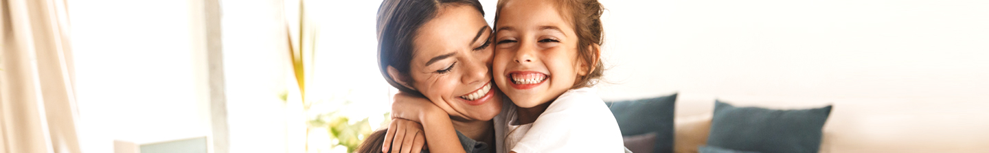 Image of happy family mother and little daughter hugging while having breakfast at home in morning